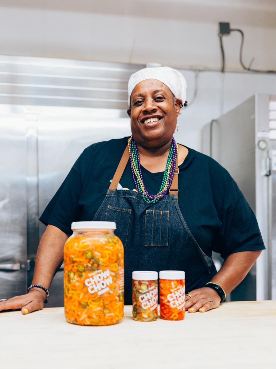 The owner of Wanda's Cooking smiles behind jars of her preserves in her kitchen.