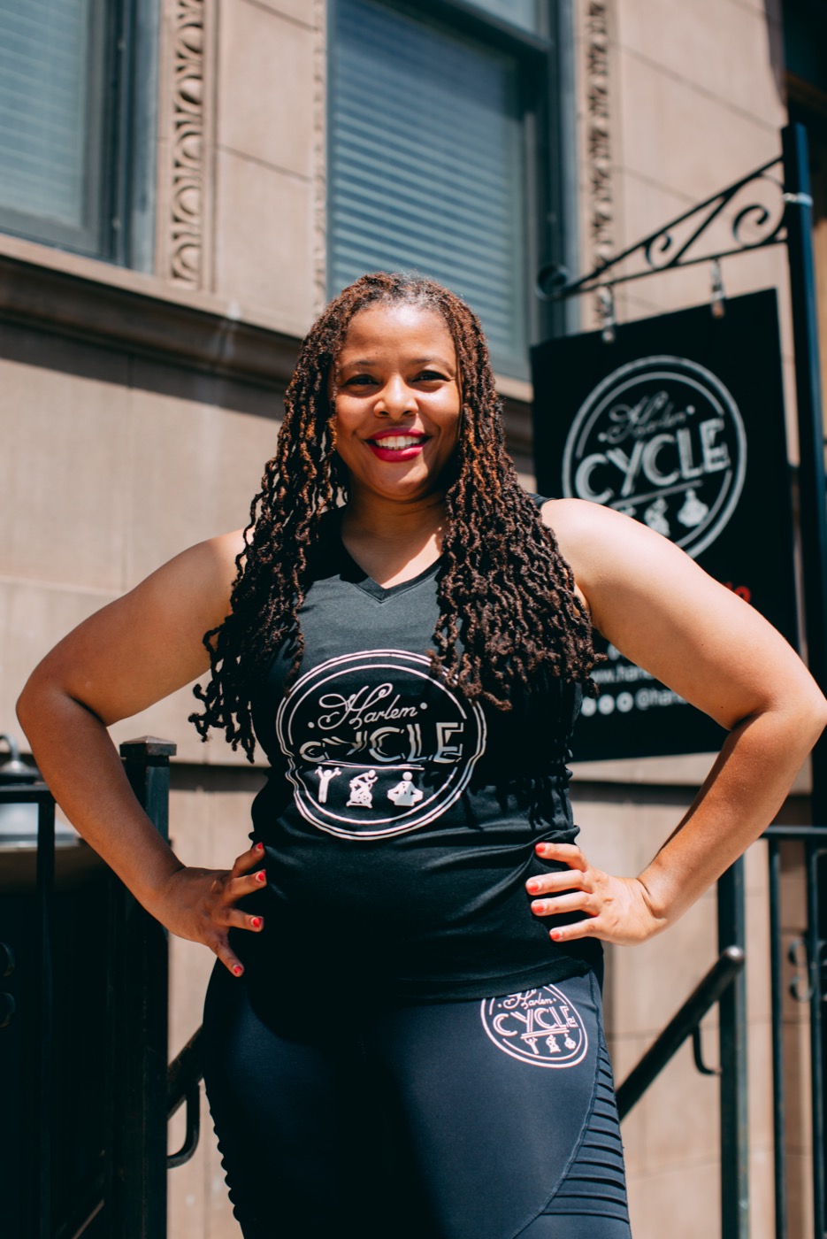 A fitness studio owner standing proudly in front of her branded storefront sign