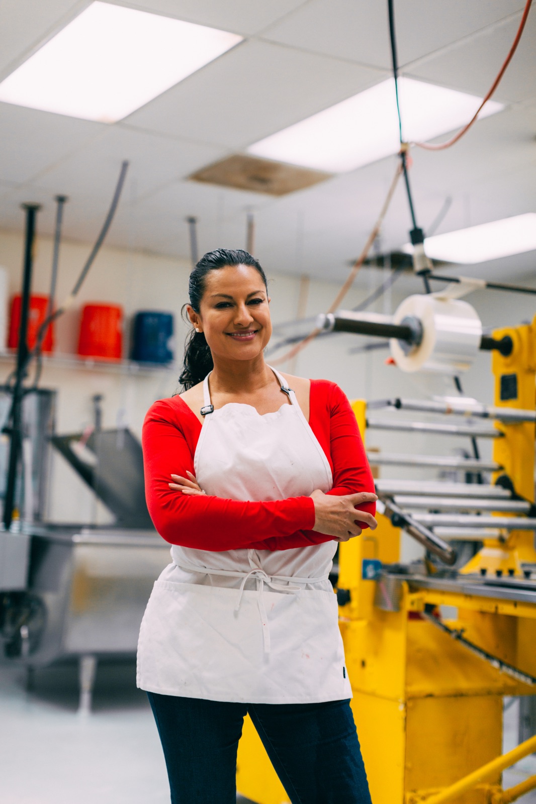 An ice pop business owner standing proudly with arms crossed in her production kitchen